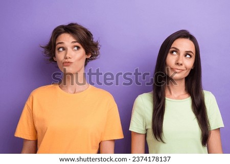Photo of doubtful suspicious ladies wear t-shirts looking empty space isolated violet color background