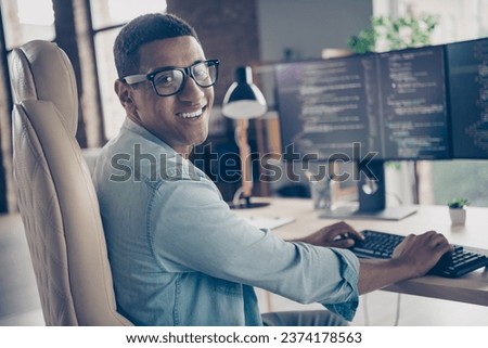 Photo of expert guy developer programmer looking at camera smiling when editing code creating new app in office workplace next to computer