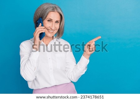 Photo of pretty charming lady wear white shirt talking modern gadget pointing empty space isolated blue color background
