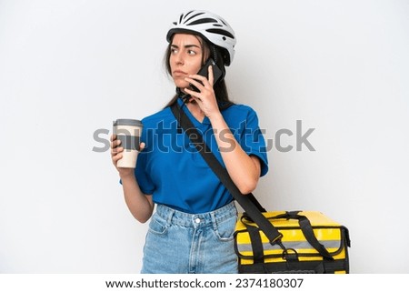Young caucasian woman with thermal backpack isolated on white background holding coffee to take away and a mobile