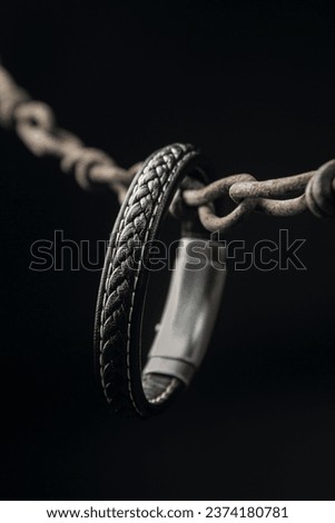 Men's leather bracelet on an iron chain on a dark background. Men's accessory