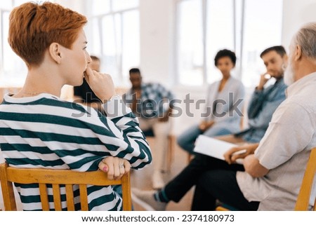 Rear view of thoughtful young woman thinking about mental problem or addiction sitting in circle during group therapy session. Concept of mental health, psychotherapy, depression, social issues. Royalty-Free Stock Photo #2374180973