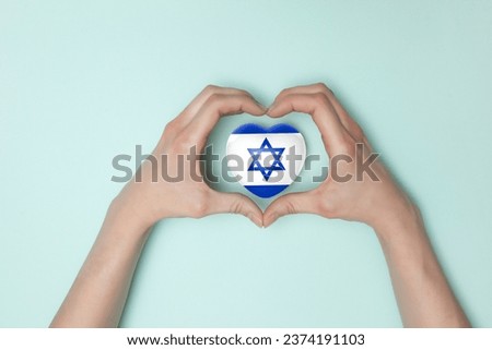 Heart with print of Israel flag in female hands. Flat lay. Copy space. Royalty-Free Stock Photo #2374191103