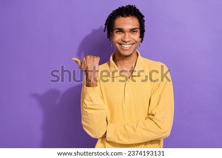 Portrait of handsome guy with stylish earrings dressed yellow shirt directing at sale empty space isolated on violet color background
