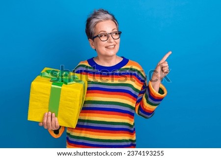 Portrait of attractive lady hold xmas giftbox look direct finger empty space isolated on blue color background
