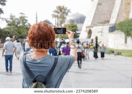 a girl on a trip takes pictures of a mosque in Istanbul on her phone
