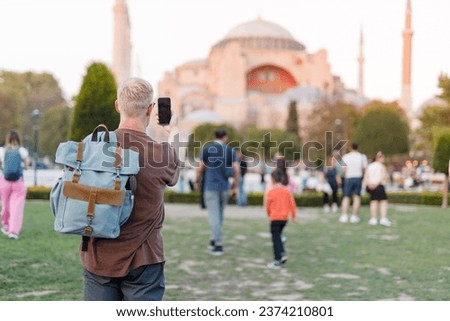 male tourist takes pictures of a mosque in Turkey on his phone