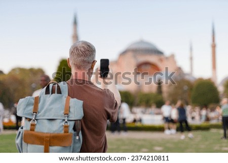male tourist takes pictures of a mosque in Turkey on his phone