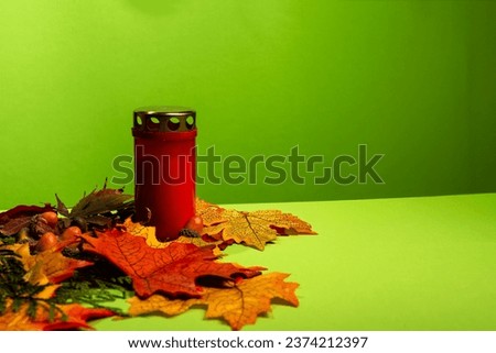 A candle stands on leaves and a green background, All Souls' Day, autumn background, autumn mood, All Souls' Day, holiday tradition