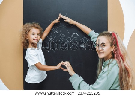 Little girl draws a family on a chalkboard