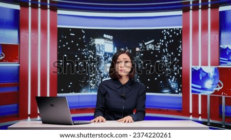 Asian news anchor hosting live broadcast to discuss about new international material on television. Woman journalist presenting world news updates, commenting on latest announcements. Royalty-Free Stock Photo #2374220261