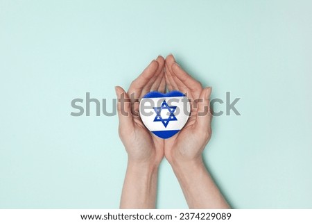 Heart with print of Israel flag in female hands. Flat lay. Copy space.