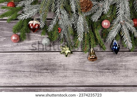 Christmas and New Year 2024 background with fir branches in snow flakes, toys and decorations on an old wooden table, banner for holiday screen, template for design. Holiday card, selective focus,