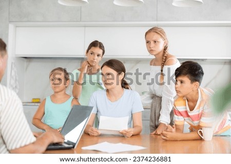 Husband with laptop does remote work, frustrated wife reads unpleasant news in letter, and alarmed children stand nearby Royalty-Free Stock Photo #2374236881