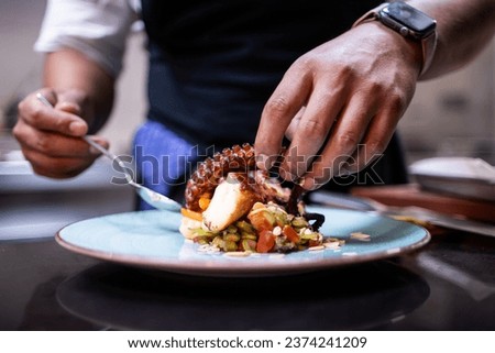 Hands finishing plating the octopus for restaurant customers Royalty-Free Stock Photo #2374241209
