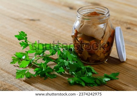 Pickled assorted mushrooms in glass jar on wooden background Royalty-Free Stock Photo #2374242975