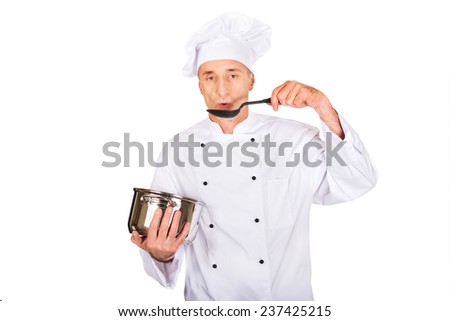 Experienced chef in white uniform tasting his soup