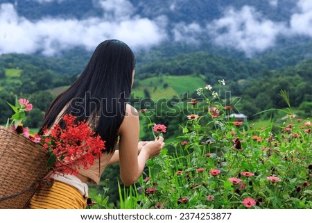 young asian woman Carry a basket to collect flowers, mountain view at morning mist green forest in the rain season background,