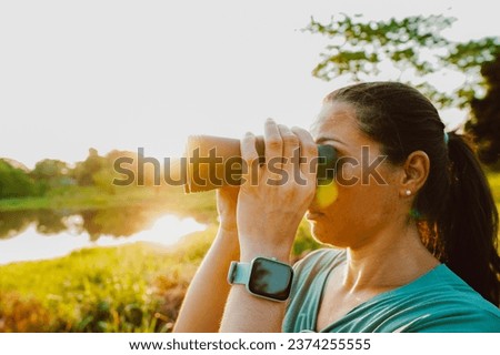 Woman looking through binoculars at the nature of Brazil. Beautiful sunset view of the Pantanal, Bonito, in Mato Grosso do Sul Royalty-Free Stock Photo #2374255555