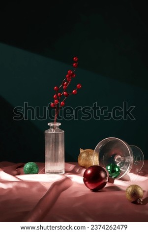 Glass pot containing red berry branch displayed with yellow, green and red baubles on the silk fabric. As Americans began to embrace Christmas as a perfect family holiday