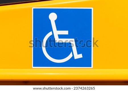 Handicapped wheelchair access logo sign on a yellow school bus.