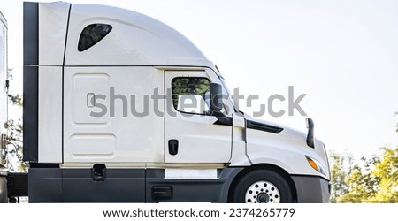 White industrial carrier big rig semi truck tractor with extended cab for truck driver rest  transporting commercial cargo in dry van semi trailer running on the highway road in California Royalty-Free Stock Photo #2374265779