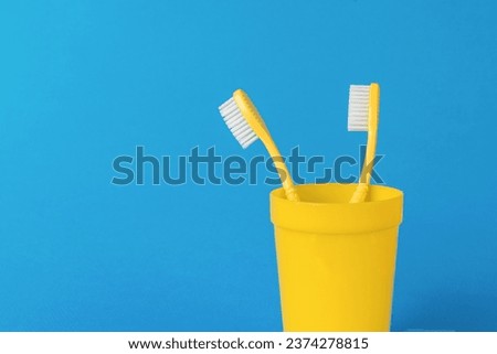 A pair of yellow toothbrushes on a bright blue background. The concept of oral care.