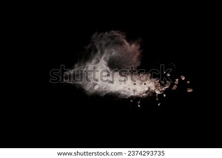 Split debris of stone exploding with white dust against black background. Royalty-Free Stock Photo #2374293735
