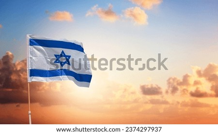 Israel flag with a star of David over beautiful sunset sky background Royalty-Free Stock Photo #2374297937