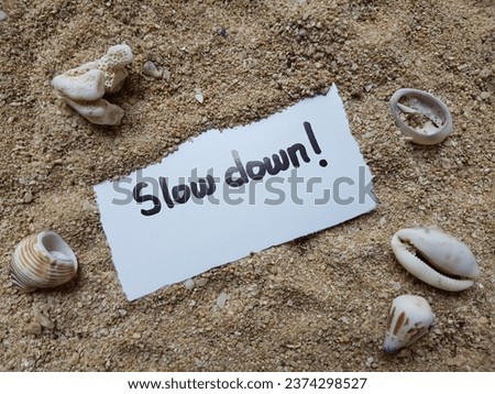 Slow down writing on beach sand background.