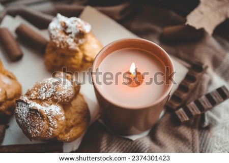 Burning candle with the smell of chocolate and cinnamon in a cozy home interior.