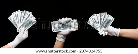 Three male hands in white medical gloves hold stacks of hundred dollar bills on a black background with copy space. Concept of payment for treatment, bribes, illegal transactions and life insurance Royalty-Free Stock Photo #2374324955
