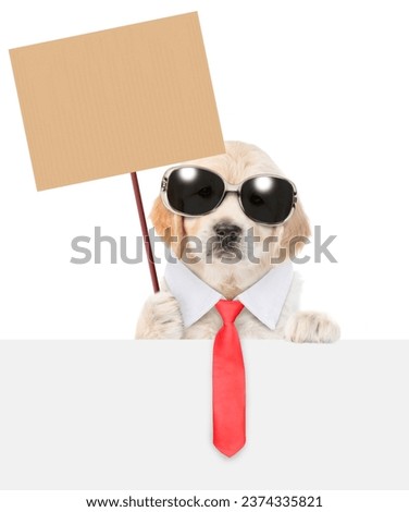 Funny smart golden retriever puppy wearing sunglasses and necktie shows empty placard above empty white banner. isolated on white background