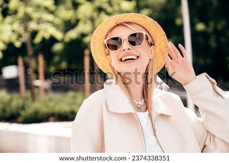 Young beautiful smiling blond woman in trendy summer clothes. Carefree female posing on the street background at sunny day. Positive model outdoors at sunset. Cheerful and happy in hat. In sunglasses