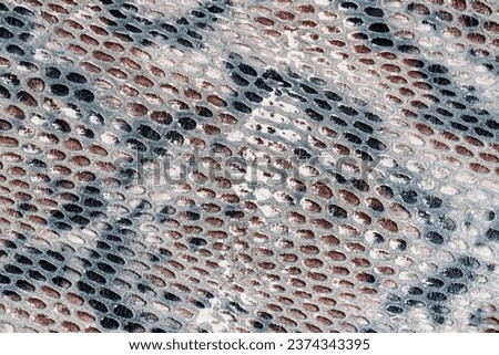 Snakeskin pattern on genuine leather close-up, imitation of exotic reptile, surface of brown grey color, trendy background