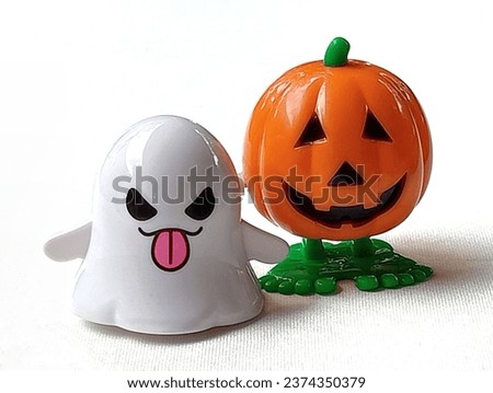 Orange pumpkin and white ghosts are smiling placed on a white background. Close -up shot of the pumpkin and ghost.