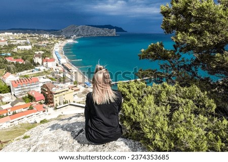 A girl on the background of a view from the Genoese fortress to the Sudak Bay. Sudak May 2021 Royalty-Free Stock Photo #2374353685