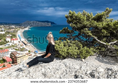 A girl on the background of a view from the Genoese fortress to the Sudak Bay. Sudak May 2021 Royalty-Free Stock Photo #2374353687