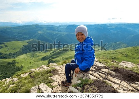 A little boy against the background of the mountains and the Bermamyt plateau in Russia. 2021