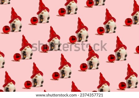 Cute ceramic Christmas gnome with red decoration bauble on pink background. Winter holiday concept. Pink Christmas pattern.