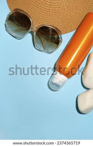 Sunscreen, stones and beach accessories on light blue background, flat lay and space for text. Sun protection
