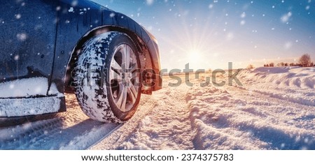 Closeup view of the car's wheel on the snowy road in natural park Royalty-Free Stock Photo #2374375783