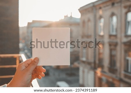 Postcard template in hands on the background of an ancient city.