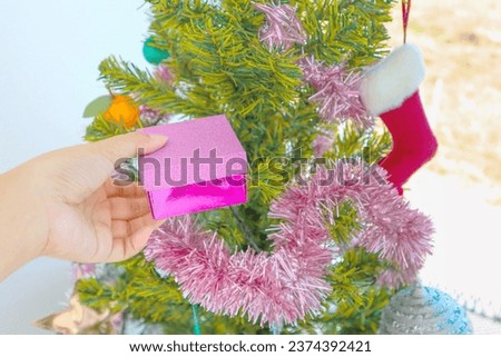 Woman holding Christmas gift with Christmas tree.