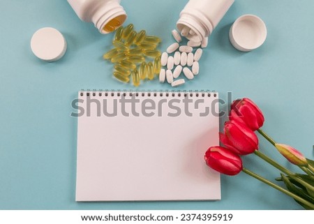 Transparent capsules with fish oil, notepad, blister, capsules and flowers on a blue background. Omega 3, vitamins recipe and prevention of viral diseases. Medical concept.