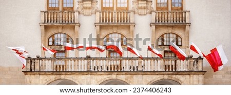 Flags of Poland on Facade Building waving in Wind. Polish Flags on Historic Building. Polish National Flag Day. 