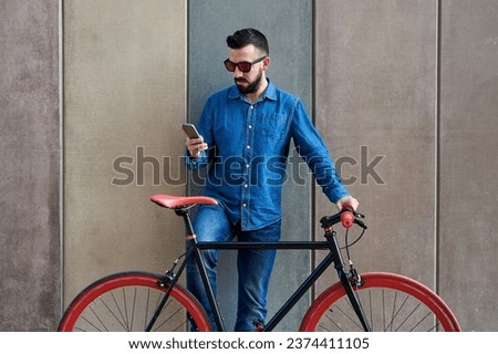 Young man on fixed gear bicycle checking his smartphone