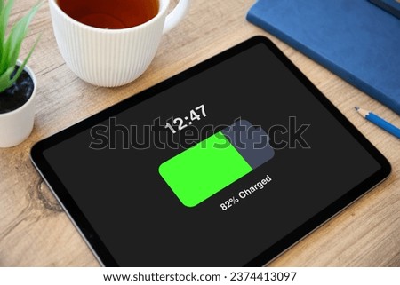 computer tablet with charged battery on screen wooden table in office