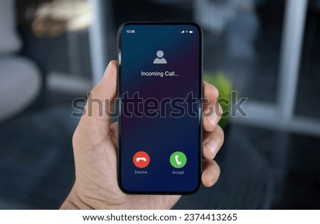 man hand hold phone with incoming call on screen in office Royalty-Free Stock Photo #2374413265