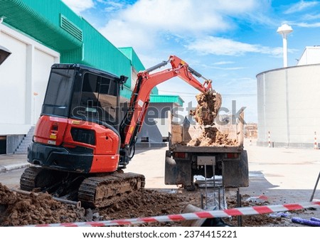 Mini excuvator dig soil load to truck in construction site.
